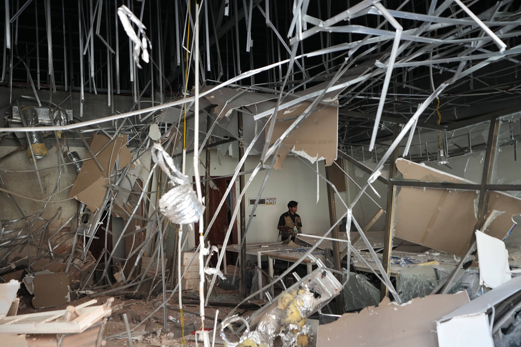 A journalist walks inside a damaged work station at a scam compound in O'Smach, Cambodia, Monday, Feb. 2, 2026, (AP Photo/Sakchai Lalit)