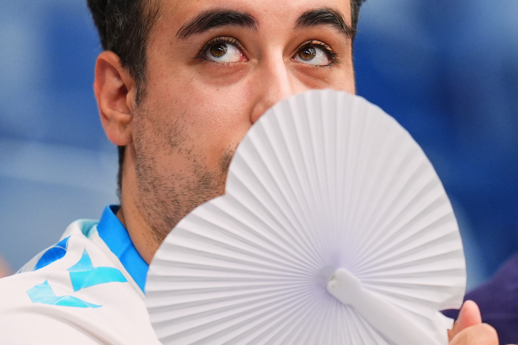 A man uses a fan to cool off during the La Liga soccer match between Real Madrid and Malaga at the Bernabeu stadium in Madrid, Spain, on Aug. 30, 2026. (AP Photo/Manu Fernandez)