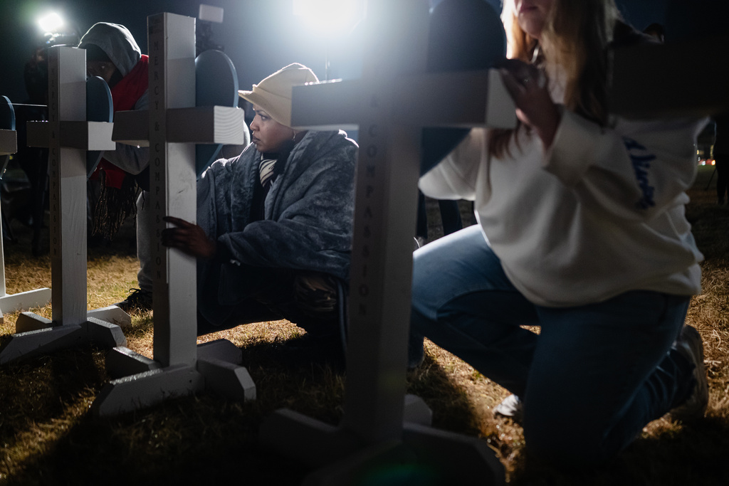 Community members sign placards on crosses during a vigil for those killed and missing after a UPS plane crashed, at the Great Lawn, Friday, Nov. 7, 2025, in Louisville, Ky. (AP Photo/Jon Cherry)
