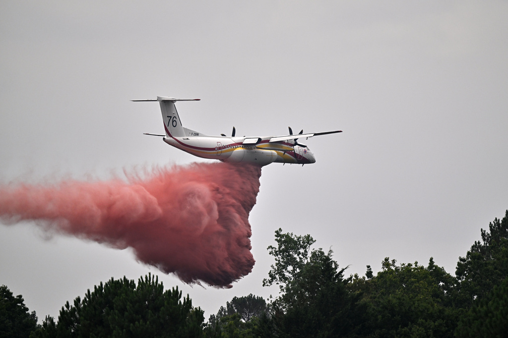 A De Havilland Canada DHC-8-400 Dash 8 operated by the French civil defense agency drops fire retardant as wildfires rage near Marcheprime, outside Bordeaux, France, Monday, July 27, 2026. (AP Photo/Emma Da Silva)