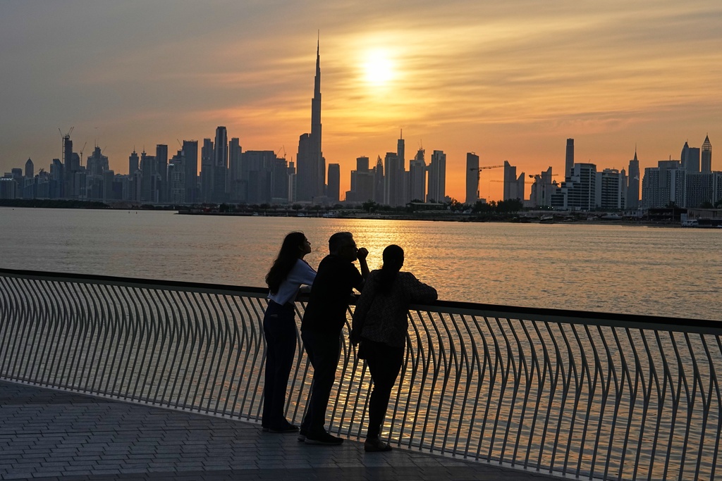 A family enjoys the sunset with the view of the city skyline and Burj Khalifa, at Dubai Creek Harbour in Dubai, United Arab Emirates, Wednesday, March 11, 2026. (AP Photo/Fatima Shbair)