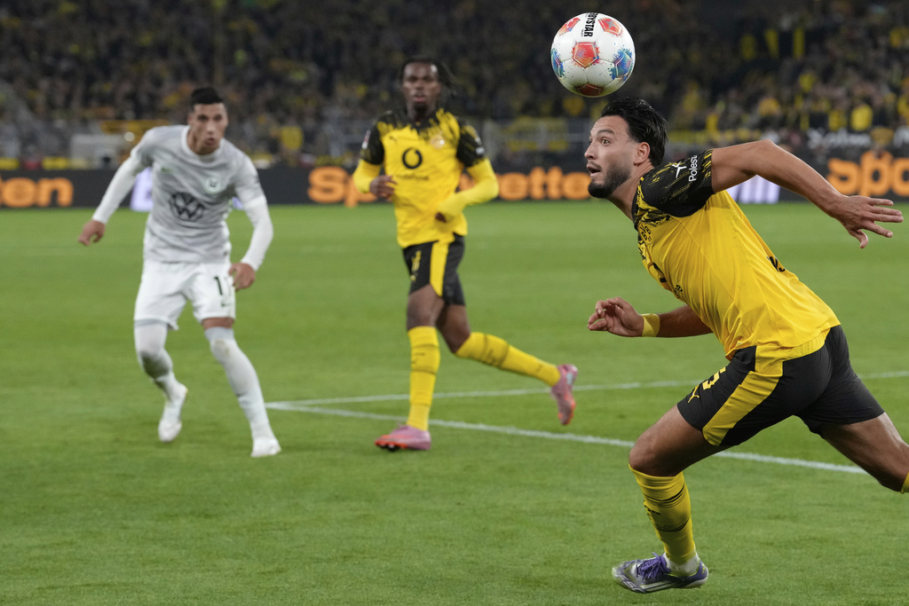 Dortmund's Ramy Bensebaini, right, heads the ball during the German Bundesliga soccer match between Borussia Dortmund and VfL Wolfsburg in Dortmund, Germany, Sunday, Sept. 21, 2025. (AP Photo/Martin Meissner)
