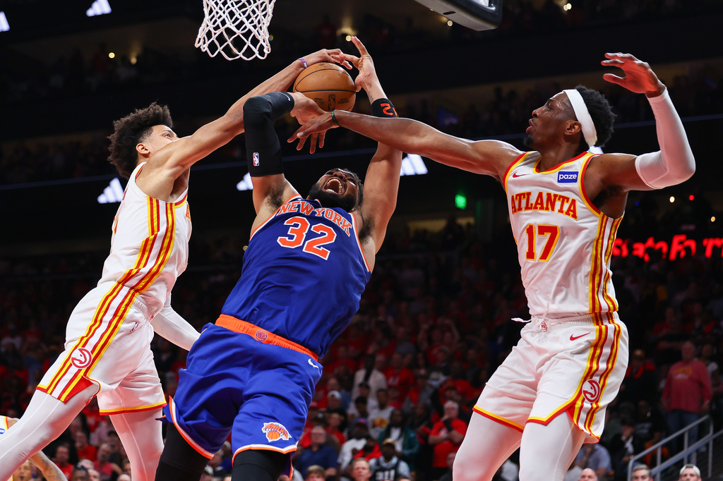Atlanta Hawks forward Jalen Johnson, left, blocks a shot from New York Knicks center Karl-Anthony Towns (32) while forward Onyeka Okongwu (17) defends during the second half in Game 3 of a first-round NBA playoffs basketball series, Thursday, April 23, 2026, in Atlanta. (AP Photo/Colin Hubbard)