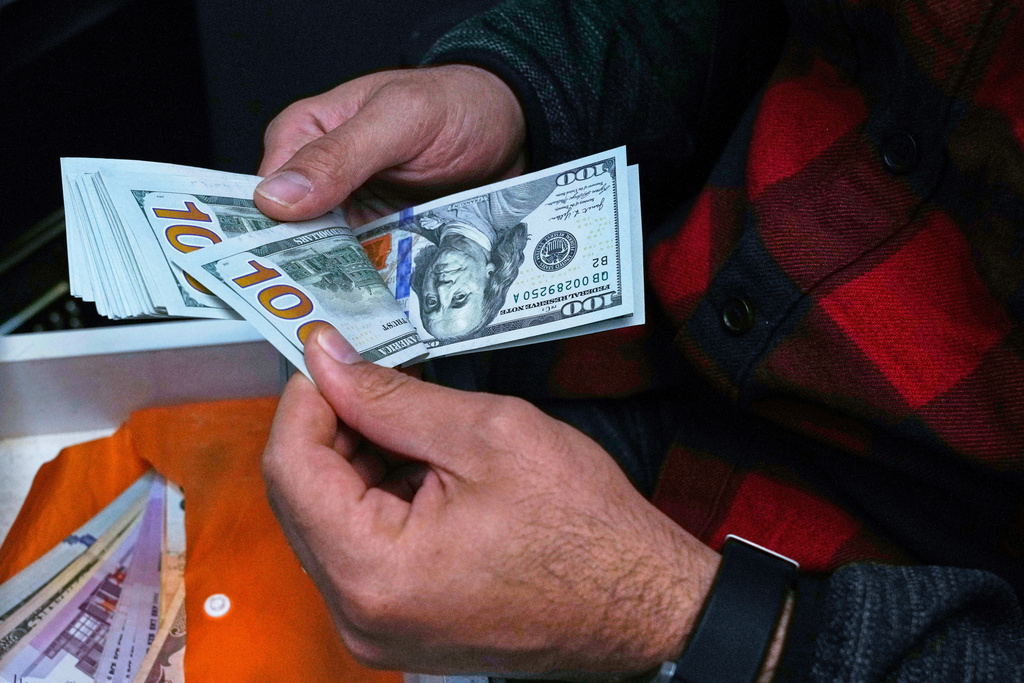 FILE- A currency exchange bureau worker counts U.S. dollars at Ferdowsi square, Tehran's go-to venue for foreign currency exchange, in downtown Tehran, Iran, April 5, 2025. (AP Photo/Vahid Salemi, File)