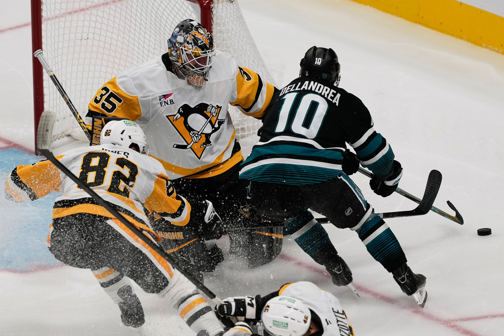 San Jose Sharks center Ty Dellandrea (10) skates toward the puck against Pittsburgh Penguins defenseman Caleb Jones (82) and goaltender Tristan Jarry (35) during the third period of an NHL hockey game in San Jose, Calif., Saturday, Oct. 18, 2025. (AP Photo/Jeff Chiu)