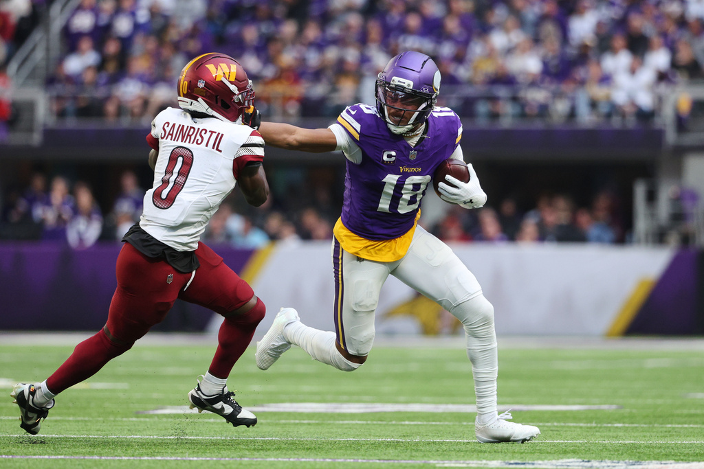 Minnesota Vikings wide receiver Justin Jefferson (18) stiff arms Washington Commanders cornerback Mike Sainristil (0) during the second half of an NFL football game, Sunday, Dec. 7, 2025, in Minneapolis. (AP Photo/Matt Krohn)