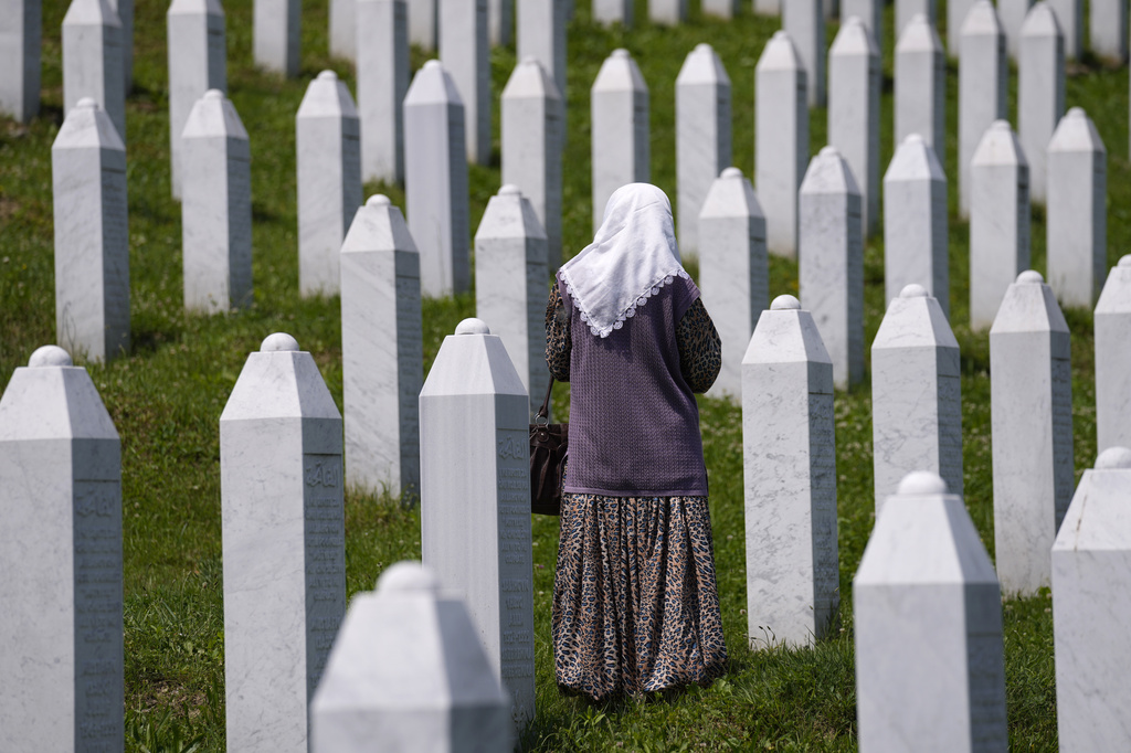 FILE - A woman walks stands among the graves of victims of the Srebrenica massacre, at the memorial cemetery in Potocari, near Srebrenica, eastern Bosnia, Tuesday, June 8, 2021, as the United Nations court in The Hague, Netherlands, delivers its verdict in the appeal by former Bosnian Serb military chief Ratko Mladic against his convictions for genocide and other crimes and his life sentence for masterminding atrocities throughout the Bosnian war. (AP Photo/Darko Bandic, File)