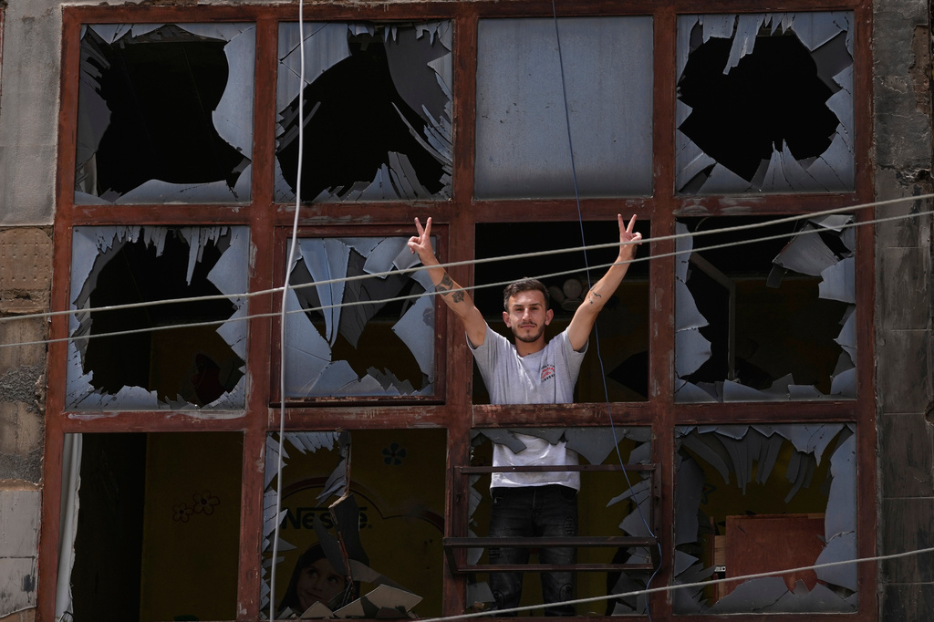 A man flashes the victory sign through the shattered window of a damaged apartment following a ceasefire between Israel and Hezbollah in the town of Nabatiyeh, southern Lebanon, Monday, June 22, 2026. (AP Photo/Mohammed Zaatari)