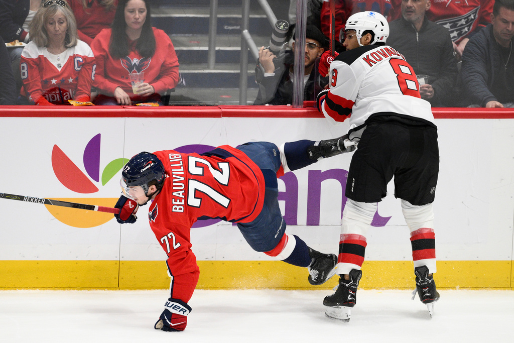 New Jersey Devils defenseman Johnathan Kovacevic (8) hits Washington Capitals right wing Anthony Beauvillier (72) during the first period of an NHL hockey game Friday, March 20, 2026, in Washington. (AP Photo/Nick Wass)