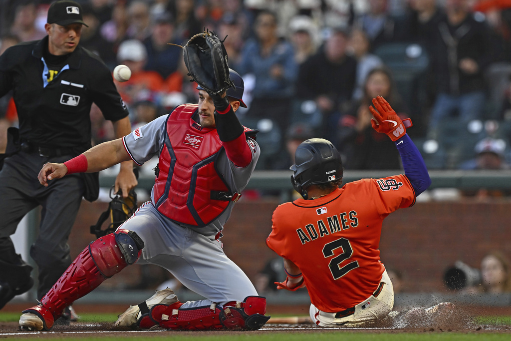 San Francisco Giants' Willy Adames (2) scores at home plate as Washington Nationals catcher Drew Millas, front left, waits for the throw in the first inning of a baseball game against the Washington Nationals in San Francisco, Friday, Aug. 8, 2025. (Jose Carlos Fajardo/Bay Area News Group via AP)
