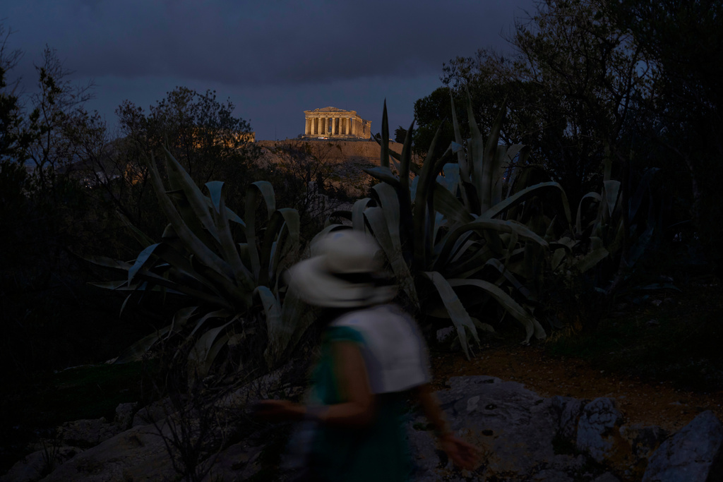 A tourist walks on Filopappos Hill with the ancient Parthenon temple atop the Acropolis in the background, in Athens, Tuesday, Oct. 21, 2025. (AP Photo/Petros Giannakouris)