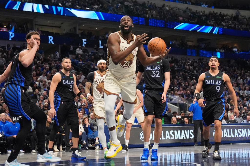 Golden State Warriors forward Draymond Green (23) is fouled driving to the basket by Dallas Mavericks' Dwight Powell, left, and Klay Thompson, Cooper Flagg (32) and Ryan Nembhard (9) look on in the first half of an NBA basketball game in Dallas, Thursday, Jan. 22, 2026. (AP Photo/Tony Gutierrez)