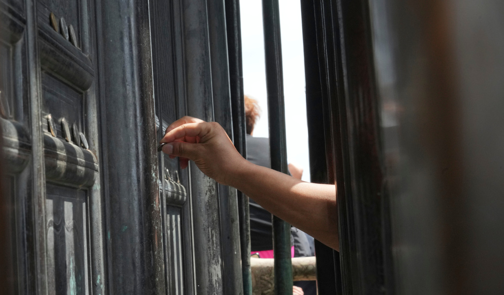 A visitor places a coin on the doors of the Golden Hall in Wudang Mountains in central China's Hubei Province on Sept. 3, 2026. (AP Photo/Achmad Ibrahim)