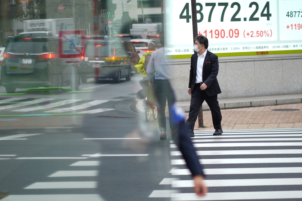 A person walks in front of an electronic stock board showing Japan's Nikkei index at a securities firm Monday, Oct. 20, 2025, in Tokyo. (AP Photo/Eugene Hoshiko)