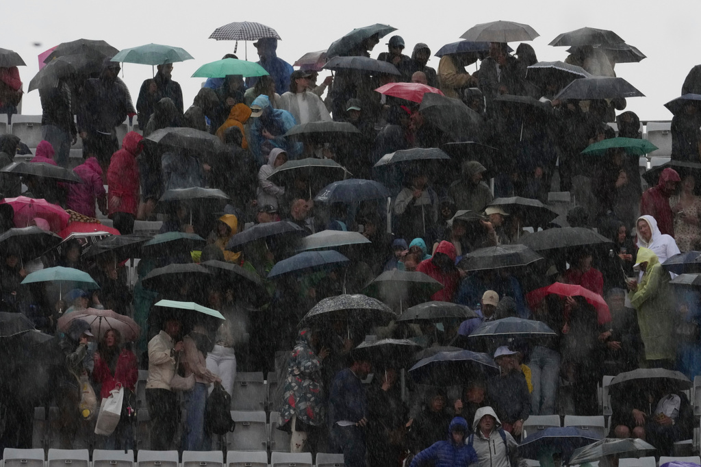 Spectators shelter from the heavy rain during a break of the semifinal match between Casper Ruud of Norway and Luciano Darderi during, at the Italian Open tennis tournament in Rome, Friday, May 15, 2026. (AP Photo/Andrew Medichini)
