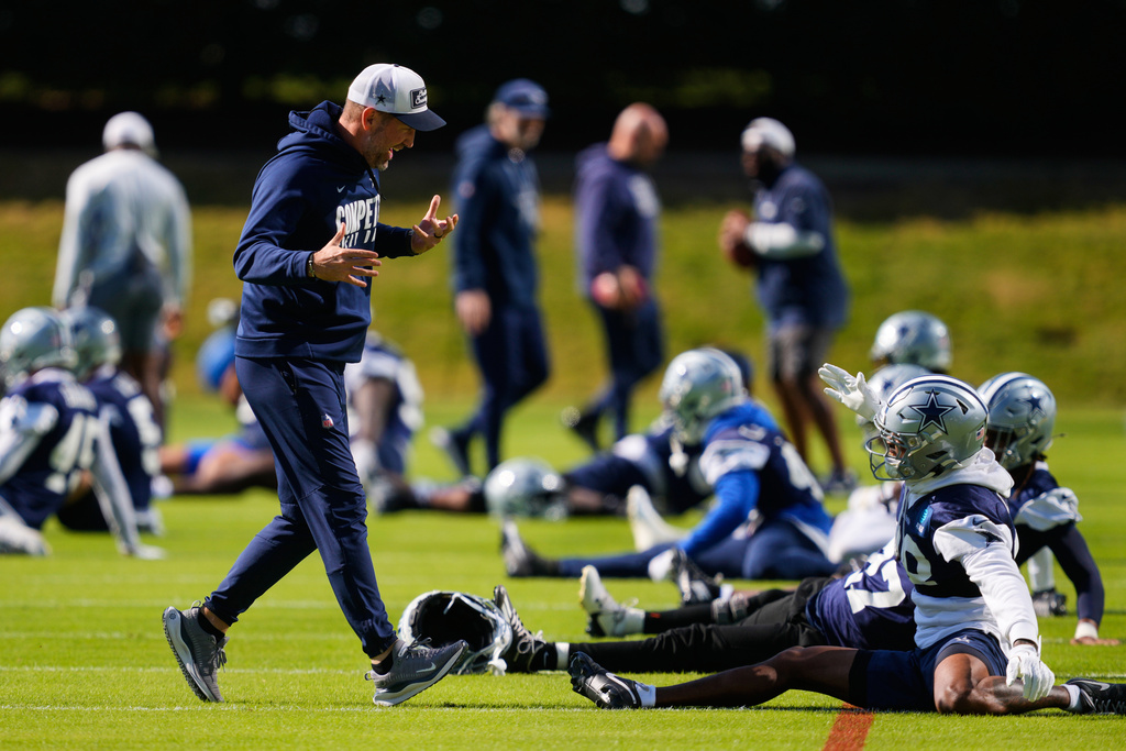 Dallas Cowboys head coach Brian Schottenheimer, left, greets players at the start of an NFL football practice at the team's headquarters Thursday, Nov. 13, 2025, in Frisco, Texas. (AP Photo/Tony Gutierrez)