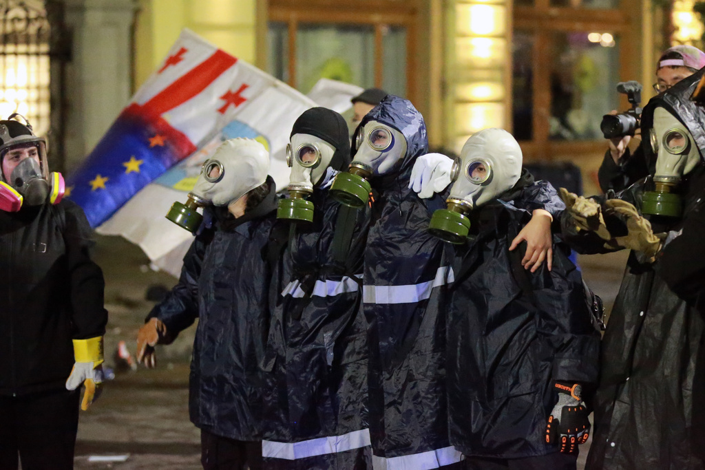 Protesters in gas masks stand in front of police during an opposition rally in the city center of Tbilisi, Georgia, on Saturday, Oct. 4, 2025, boycotting the municipal elections and call for the release of political opponents. (AP Photo/Zurab Tsertsvadze)