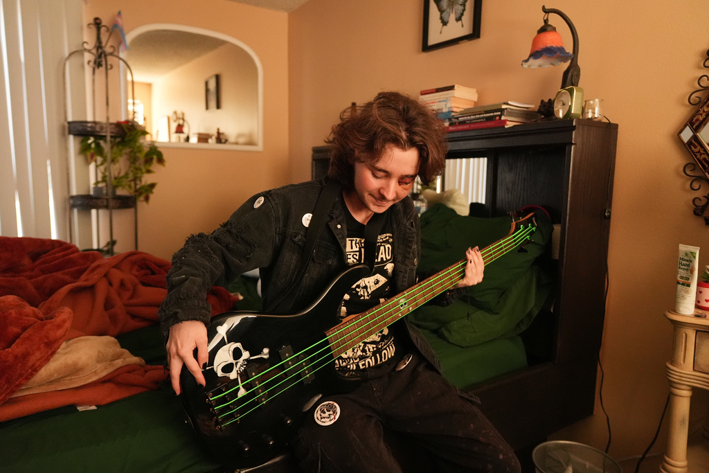 Kaden Rummler, who was injured after being hit with a projectile fired by a federal agent during a protest outside an immigration building in Santa Ana, Calif., plays the bass at home Wednesday, Jan. 14, 2026, in Southern California. (AP Photo/Damian Dovarganes)