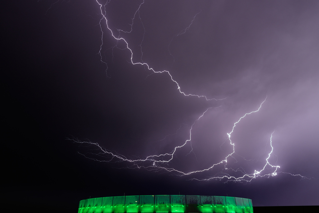 Lightning flashes beyond an office building as a thunderstorm passes in the distance, Monday, April 13, 2026, in Lenexa, Kan. (AP Photo/Charlie Riedel)