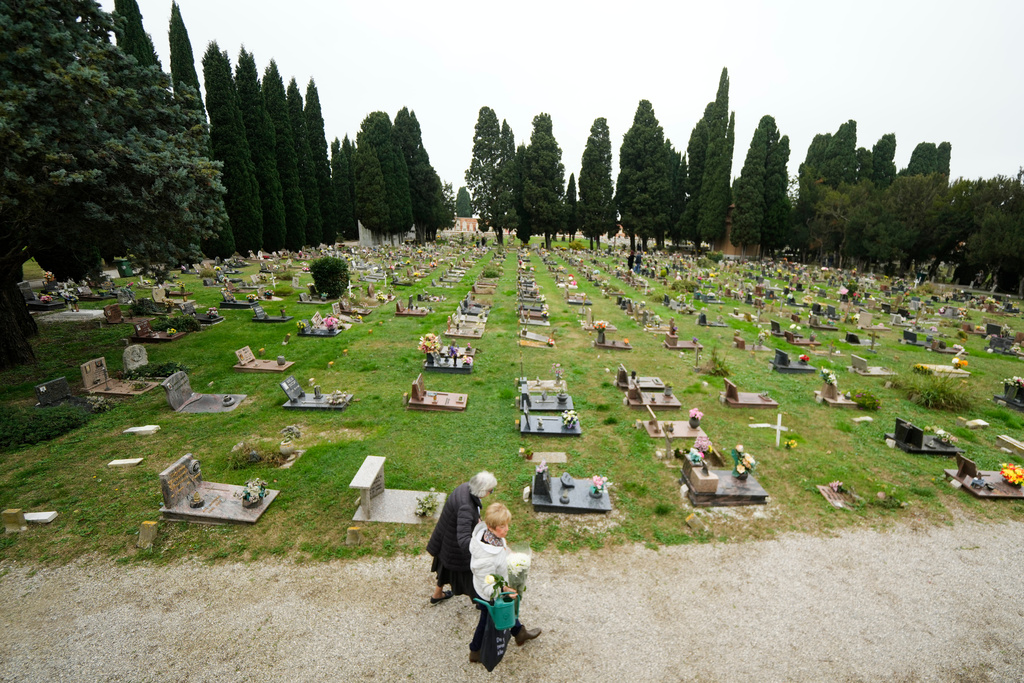 Mourners walk at the San Michele cemetery on the island of San Michele to pay respects to their dead on All Soul's Day, in Venice, Italy, Sunday, Nov. 2, 2025. (AP Photo/Luca Bruno)