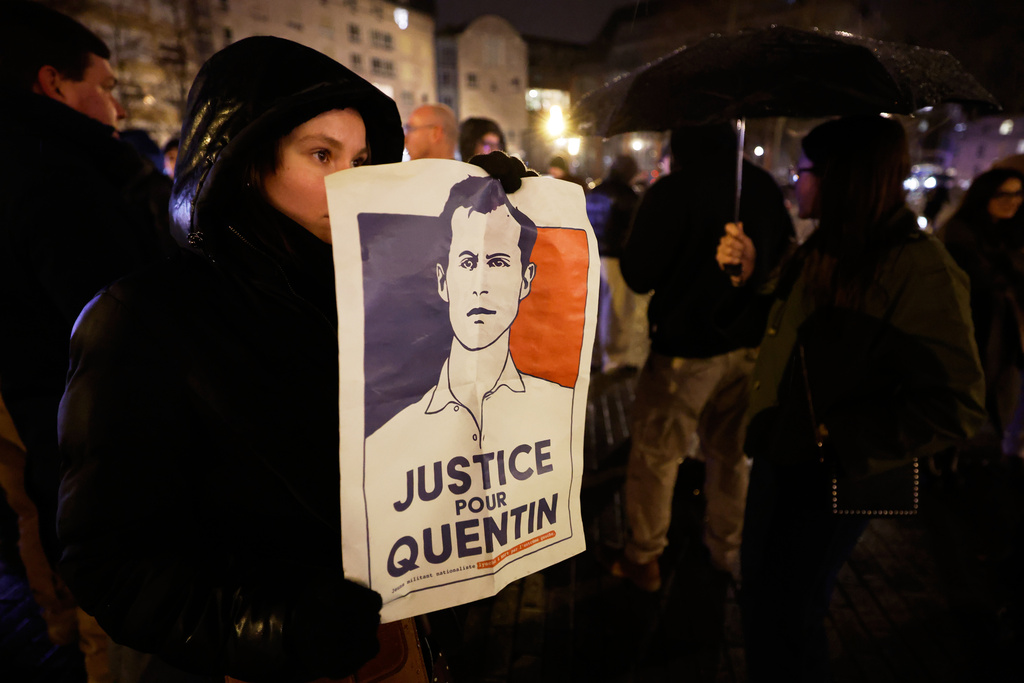 A woman holds a placard reading "Justice for Quentin" as she pays tribute to far-right student, Quentin Deranque, 23, who died in Lyon from a street beating during clashes between far-left and far-right militants, in Lille, northern France, Wednesday, Feb. 18, 2026. (AP Photo/Jean-Francois Badias)
