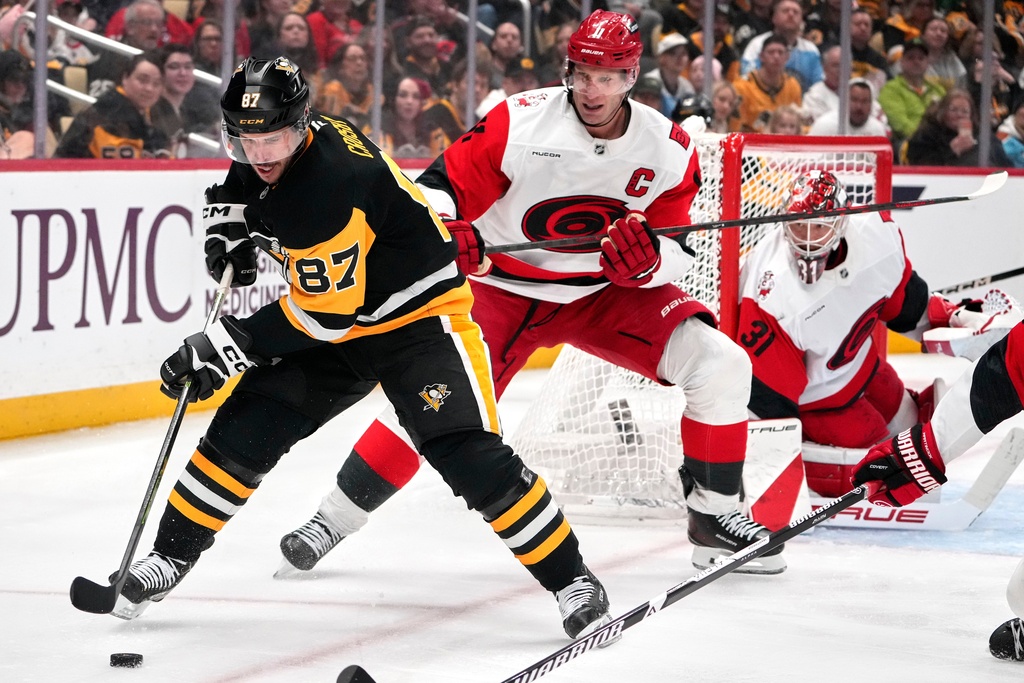 Pittsburgh Penguins' Sidney Crosby (87) is defended by Carolina Hurricanes' Jordan Staal (11) during the second period of an NHL hockey game in Pittsburgh, Sunday, March 22, 2026. (AP Photo/Gene J. Puskar)