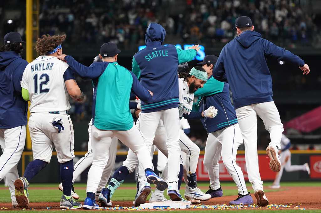 Seattle Mariners' J.P. Crawford, center facing, celebrates with teammates after hitting a game-winning RBI single against the Houston Astros during the ninth inning of a baseball game, Saturday, April 11, 2026, in Seattle. (AP Photo/Lindsey Wasson)