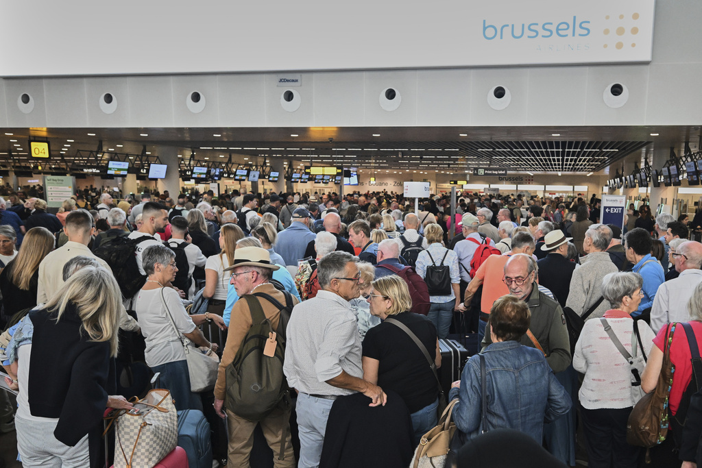 People stand in a line to check in after a cyber attack caused delays at Brussels International Airport in Zaventem, Belgium, Saturday, Sept. 20, 2025. (AP Photo/Harry Nakos)