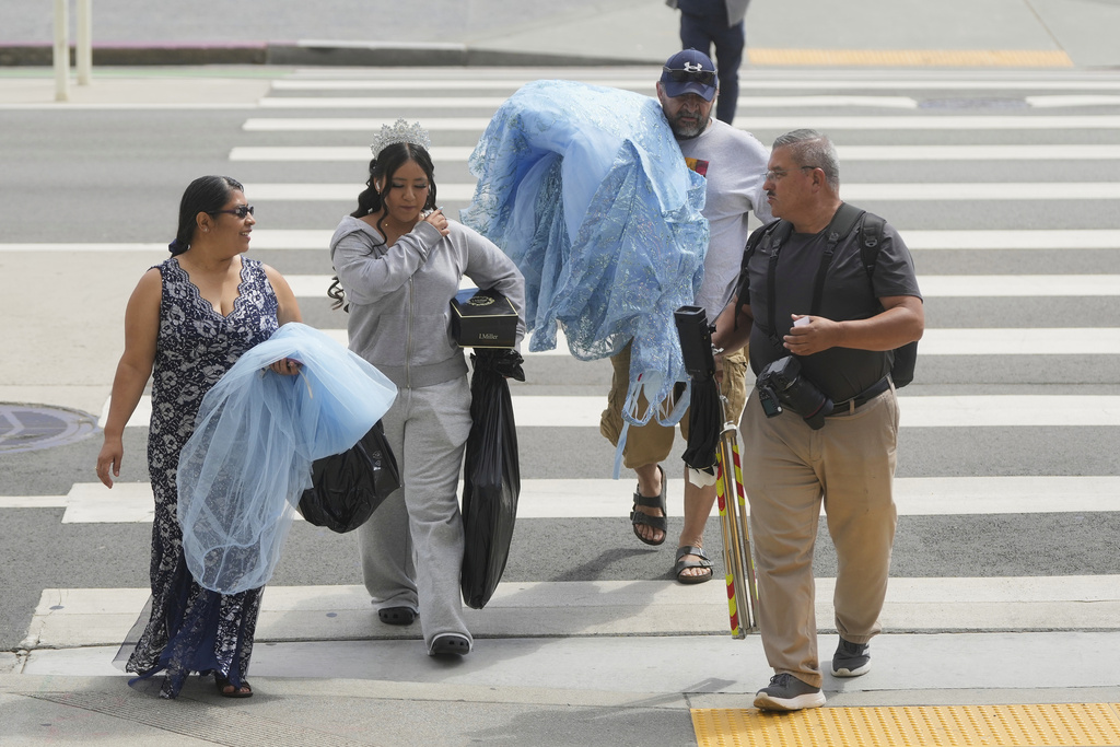 Photographer Miguel Plascencia, right, talks with Abbie Gonzalez, second from left, as she arrives with her mother Anna Gonzalez and mother's boyfriend William Umanzor to City Hall for Abbie's quinceañera portrait session in San Francisco, Monday, Aug. 25, 2025. (AP Photo/Jeff Chiu)