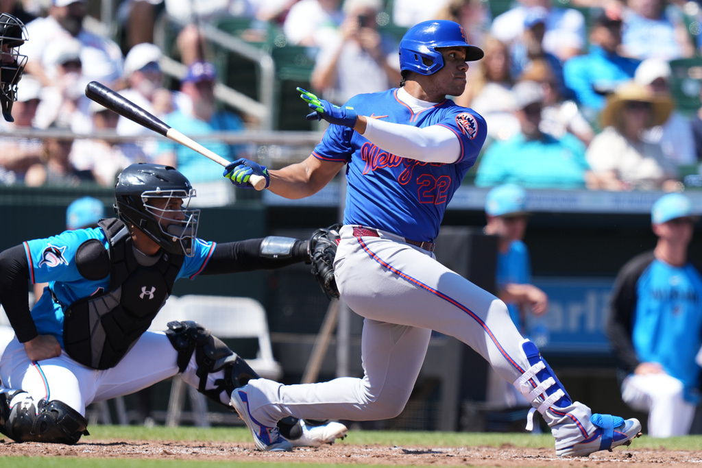 New York Mets' Juan Soto, right, hits a single during the fourth inning of a spring training baseball game against the Miami Marlins, Sunday, March 22, 2026, in Jupiter, Fla. (AP Photo/Lynne Sladky)