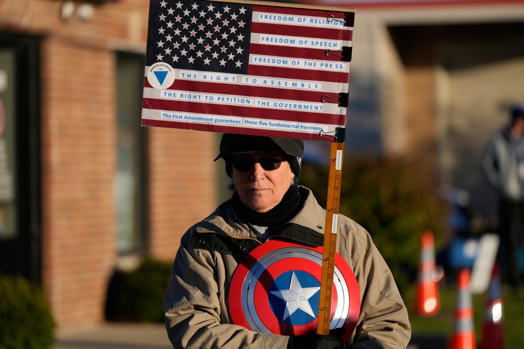 Jeanette Mancusi holds a flag as protesters gather outside an ICE processing facility in Broadview, Ill. a suburb of Chicago, Friday, Oct. 24, 2025. (AP Photo/Nam Y. Huh)