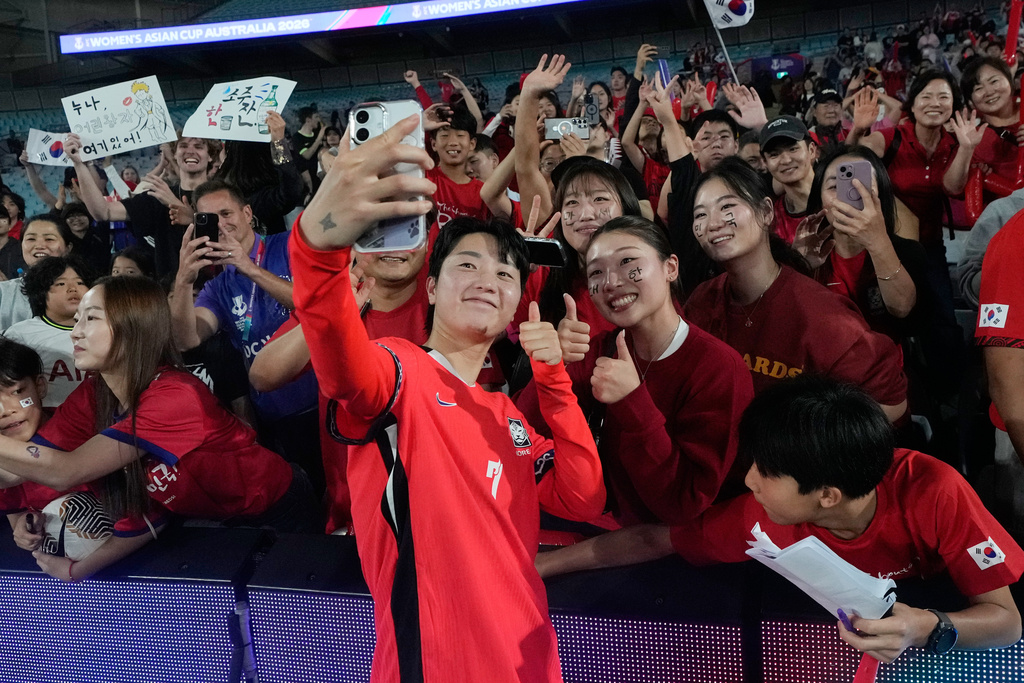 South Korea's Son Hwa-yeon takes a selfie with fans following the Women's Asian Cup quarterfinal soccer match between South Korea and Uzbekistan in Sydney, Saturday, March 14, 2026. (AP Photo/Rick Rycroft)