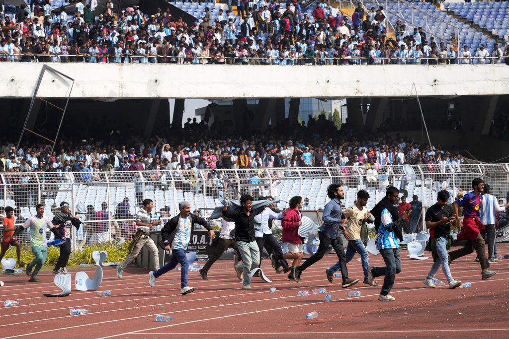 Indian fans vandalize stadium chairs as they run on to the field after failing to get a glimpse of Argentine soccer star Lionel Messi at the Salt Lake Stadium, in Kolkata, India, Saturday, Dec. 13, 2025. (AP Photo/Bikas Das)