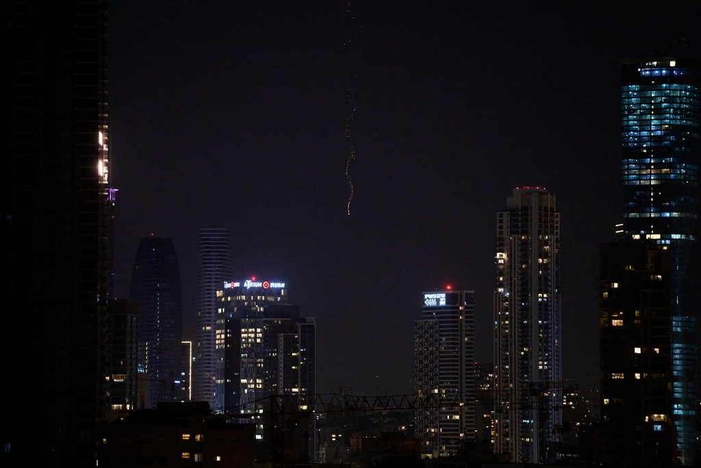 Missiles launched from Iran streak across the sky over central Israel, early Monday, March 23, 2026. (AP Photo/Ohad Zwigenberg)