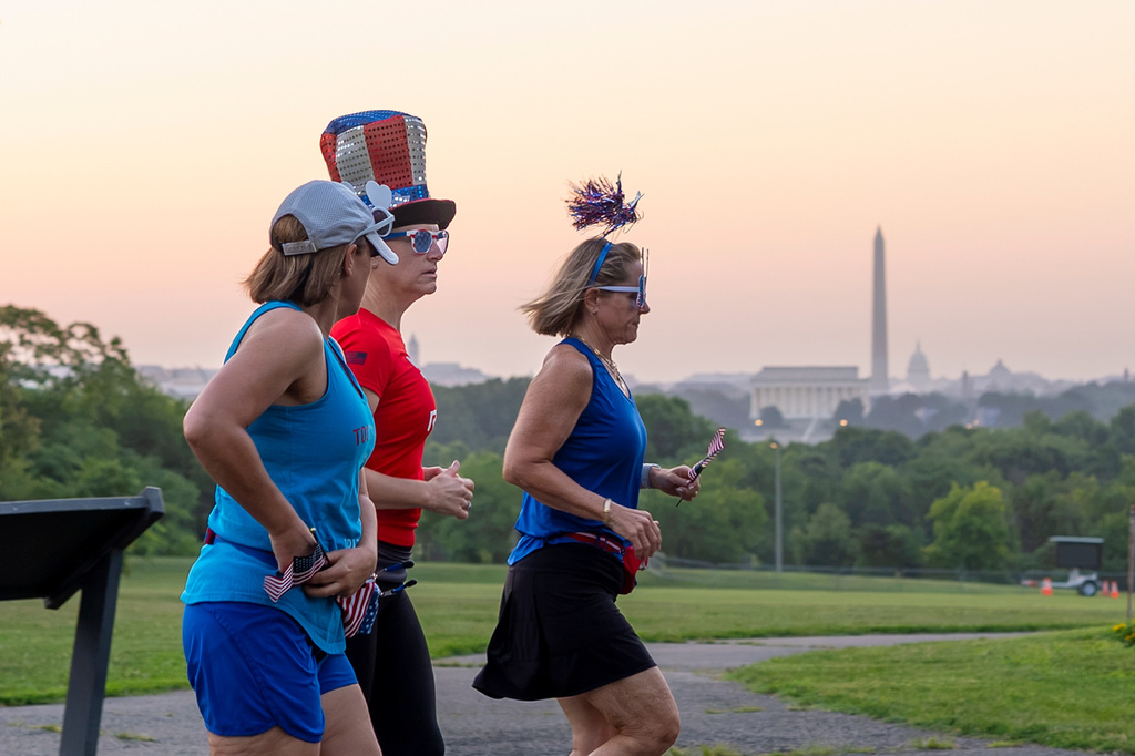 Runners wearing Independence Day-themed items jog at dawn past an overlook in Arlington, Va., as Washington prepares for sweltering temperatures, Friday, July 3, 2026. (AP Photo/J. Scott Applewhite)