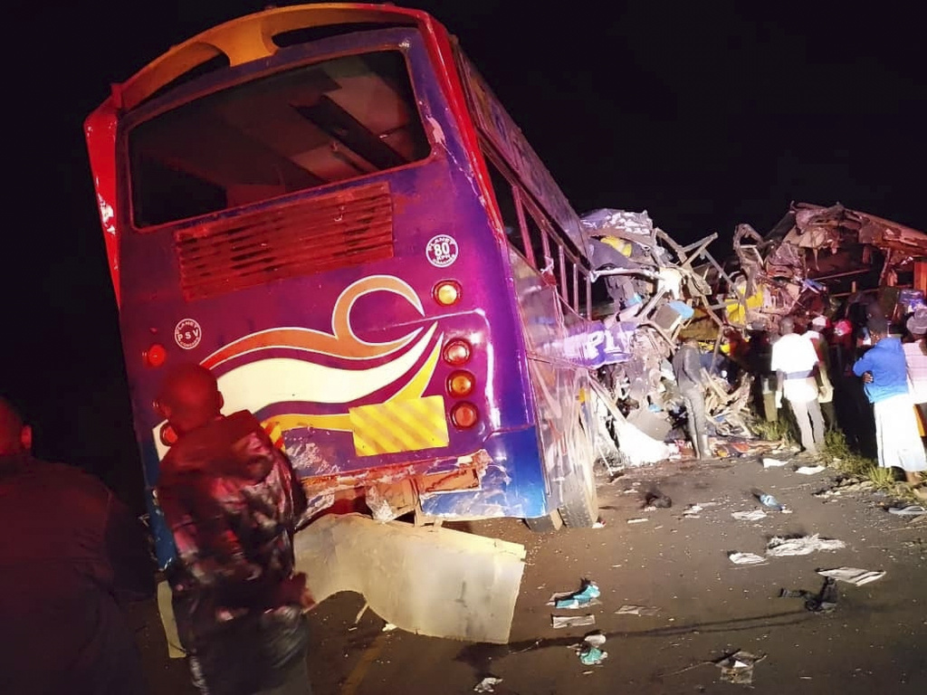 People gather near the wreckage of a bus involved in a collision that left several people dead near Kiryandongo on the highway from the Ugandan capital of Kampala to the city of Gulu in northern Uganda, Wednesday, Oct. 22, 2025. (AP Photo/Uganda Red Cross )