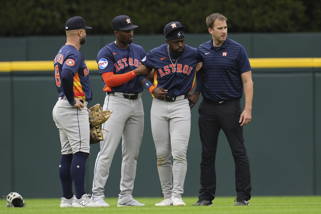 Houston Astros center fielder Taylor Trammell, second from right, is helped after being injured attempting to catch a Detroit Tigers' Dillon Dingler fly ball in the first inning during a baseball game Wednesday, Aug. 20, 2025, in Detroit. (AP Photo/Paul Sancya)