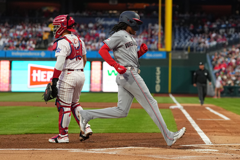 Washington Nationals' CJ Abrams, right, score past Philadelphia Phillies catcher Rafael Marchán, left, during the first inning of a baseball game, Monday, March 30, 2026, in Philadelphia. (AP Photo/Matt Rourke)