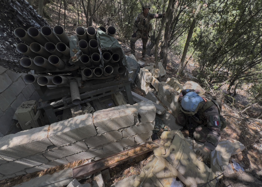 A French U.N. peacekeeper, foreground, checks ammunition boxes next to a destroyed Hezbollah rocket launcher in the Saluki Valley, south Lebanon, Wednesday, Aug. 20, 2025. (AP Photo/Hussein Malla)