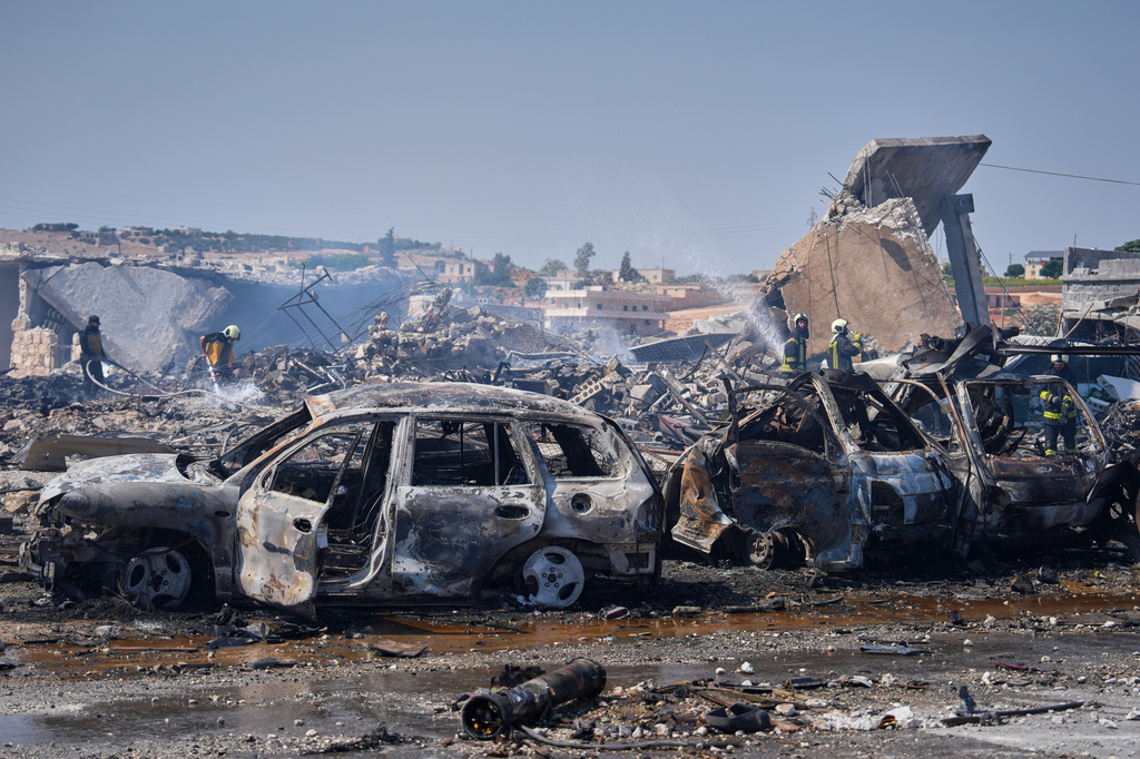 Firefighters work among rubble and burned-out vehicles at the site of an explosion at what Syria's Defense Ministry said was a warehouse used for the temporary storage of weapons near Sarmada, in Idlib province, Syria, Wednesday, Sept. 9, 2026. (AP Photo/Omar Albam)