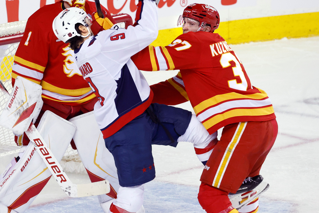 Washington Capitals' Ryan Leonard, front left, and Calgary Flames' Yan Kuznetsov, right, battle in front of the Flames' net during second-period NHL hockey game action in Calgary, Alberta, Friday, Jan. 23, 2026. (Larry MacDougal/The Canadian Press via AP)