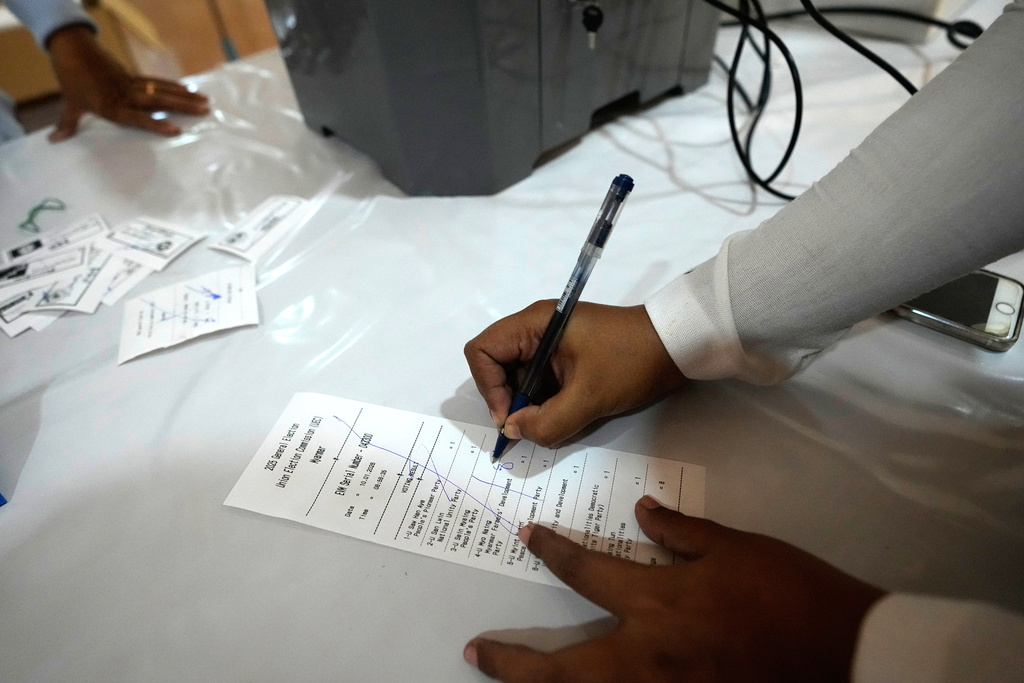 An official of the Union Election Commission checks a sample slip from an electronic voting machine as they prepare to set up a polling station opened at a monastery one day before the second phase of the general election in Yangon, Myanmar, Saturday, Jan. 10, 2026. (AP Photo/Thein Zaw)