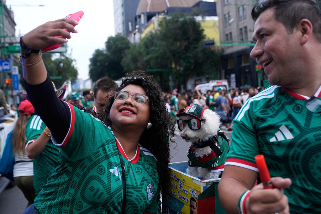 A fan, left, takes a photo with a dog named Osito, wearing a Mexico national soccer team jersey, next to Jorge Rangel before the World Cup Group A soccer match against South Korea in Mexico City, Thursday, June 18, 2026. (AP Photo/Marco Ugarte)