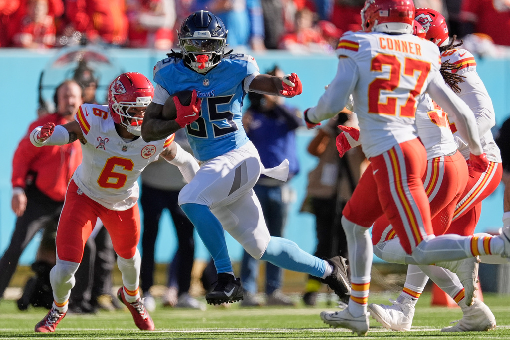 Tennessee Titans tight end Chig Okonkwo (85) runs for a first down between Kansas City Chiefs safety Bryan Cook (6) and safety Chamarri Conner (27) during the first half of an NFL football game Sunday, Dec. 21, 2025, in Nashville, Tenn. (AP Photo/George Walker IV)