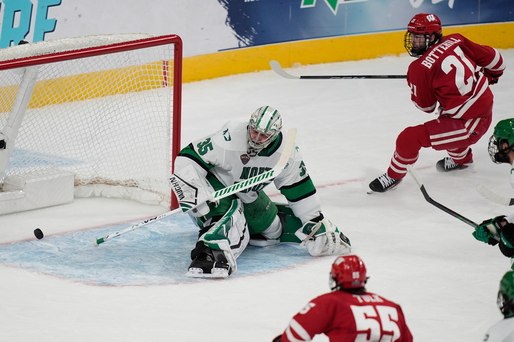Wisconsin forward Ryan Botterill (21) scores against North Dakota goaltender Jan Spunar (35) in the first period of a semifinal game of the NCAA Frozen Four men's college hockey tournament Thursday, April 9, 2026, in Las Vegas. (AP Photo/John Locher)