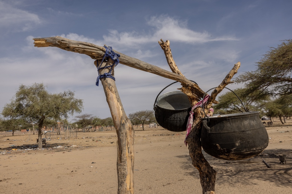 Cooking pots are hung from a wooden post in the makeshift refugee camp near Douankara, Hodh El Chargui Region, Mauritania, on the border with Mali, Nov. 6, 2025. (AP Photo/Caitlin Kelly)