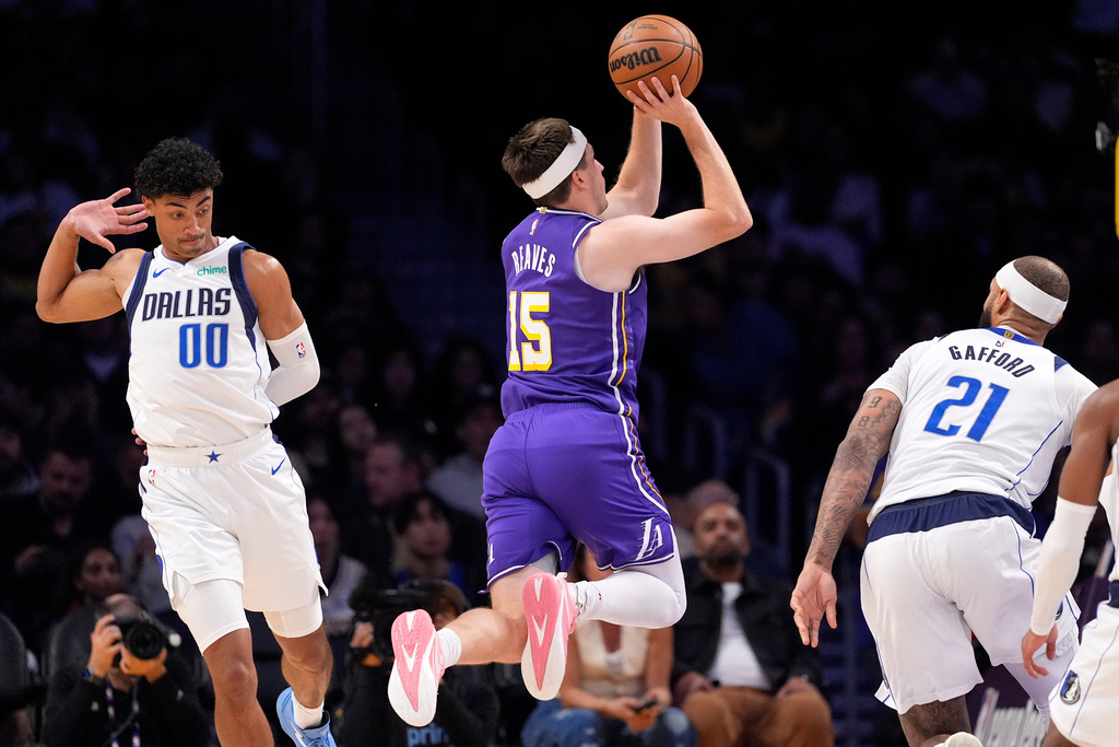 Los Angeles Lakers guard Austin Reaves, center, shoots as Dallas Mavericks guard Max Christie, left, and forward Daniel Gafford defend during the first half of an NBA basketball game Thursday, Feb. 12, 2026, in Los Angeles. (AP Photo/Mark J. Terrill)