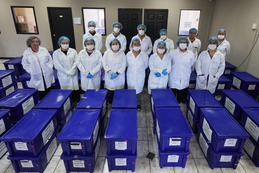Archivists pose for a group photo with boxes containing testimonies from victims of the internal armed conflict between 1960 and 1996, who sought reparations for the abuses they suffered, in Guatemala City, Wednesday, July 22, 2026. (AP Photo/Moises Castillo)