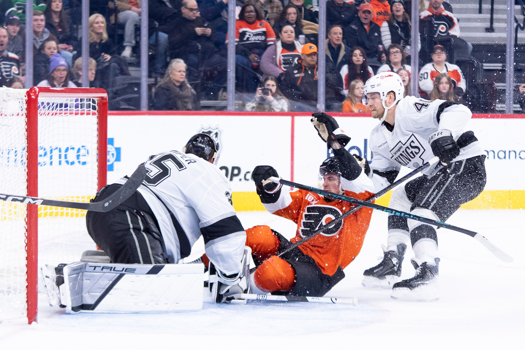 Philadelphia Flyers' Trevor Zegras, center, slides into Los Angeles Kings' Darcy Kuemper, left, as Joel Armia, right, is behind him during the second period of an NHL hockey game, Saturday, Jan. 31, 2026, in Philadelphia. (AP Photo/Chris Szagola)