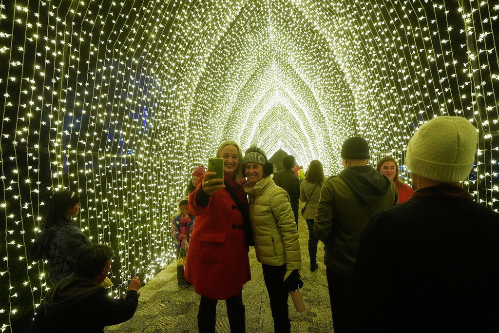People take photos while walking through the San Francisco Botanical Garden's Winter Cathedral exhibit for Lightscape at Golden Gate Park in San Francisco, Wednesday, Dec. 17, 2025. (AP Photo/Jeff Chiu)